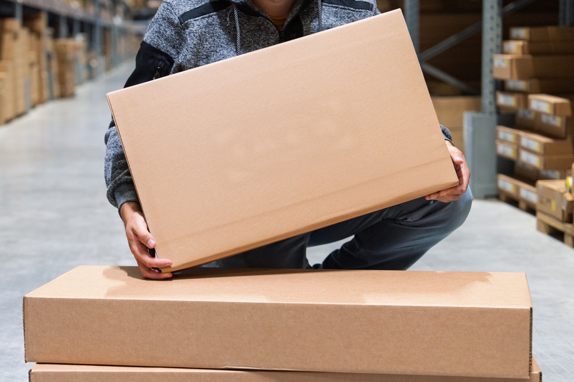 Warehouse Worker Lifting Cardboard Box for Inventory and Shipment Preparation Process